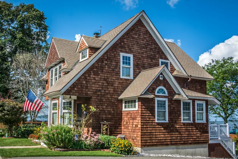 Shingle-style American home with a flag on the porch